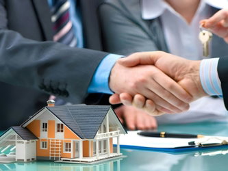 Two men shaking hands over a house model and keys